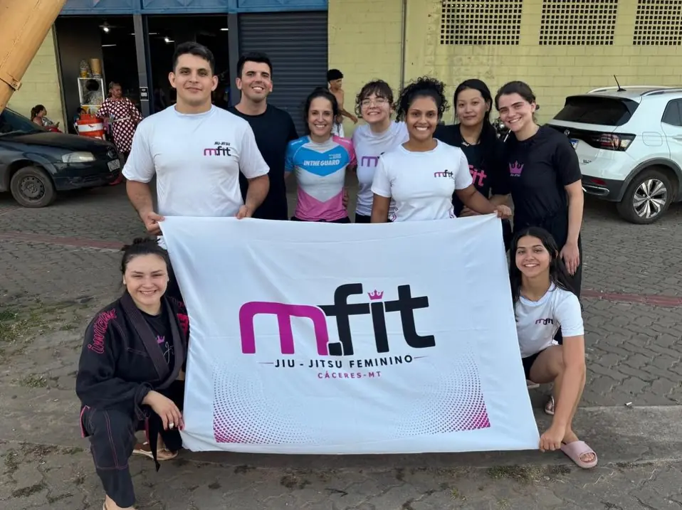 Equipe da MFIT com a bandeira de jiu-jitsu feminino em dia de campeonato