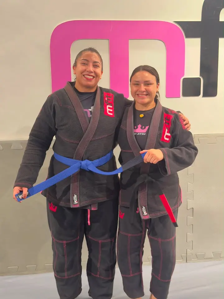 Duas alunas de kimono preto segurando a nova faixa azul
