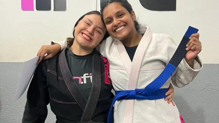 Duas alunas abraçadas mostrando a faixa azul no dia da graduação