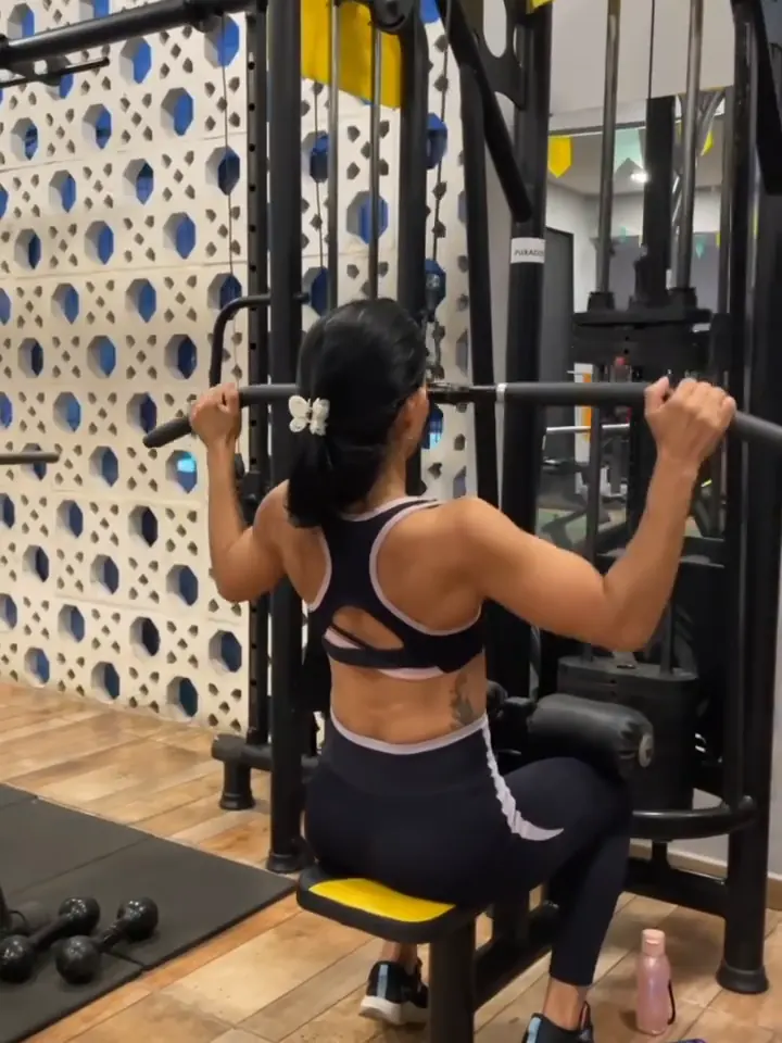 Aluna treinando puxada na polia na sala de musculação