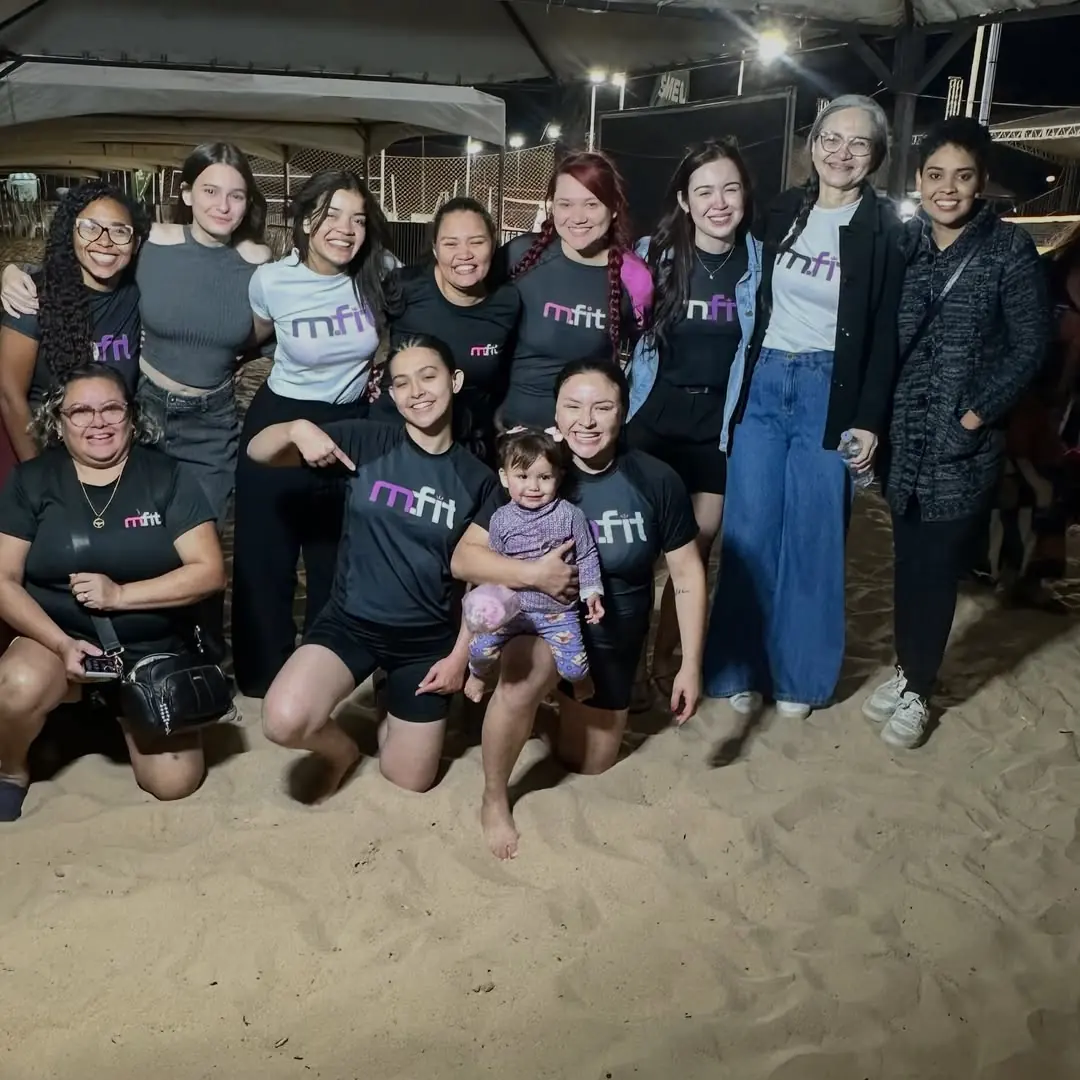 Alunas e famílias da MFIT reunidas à noite em um evento na areia