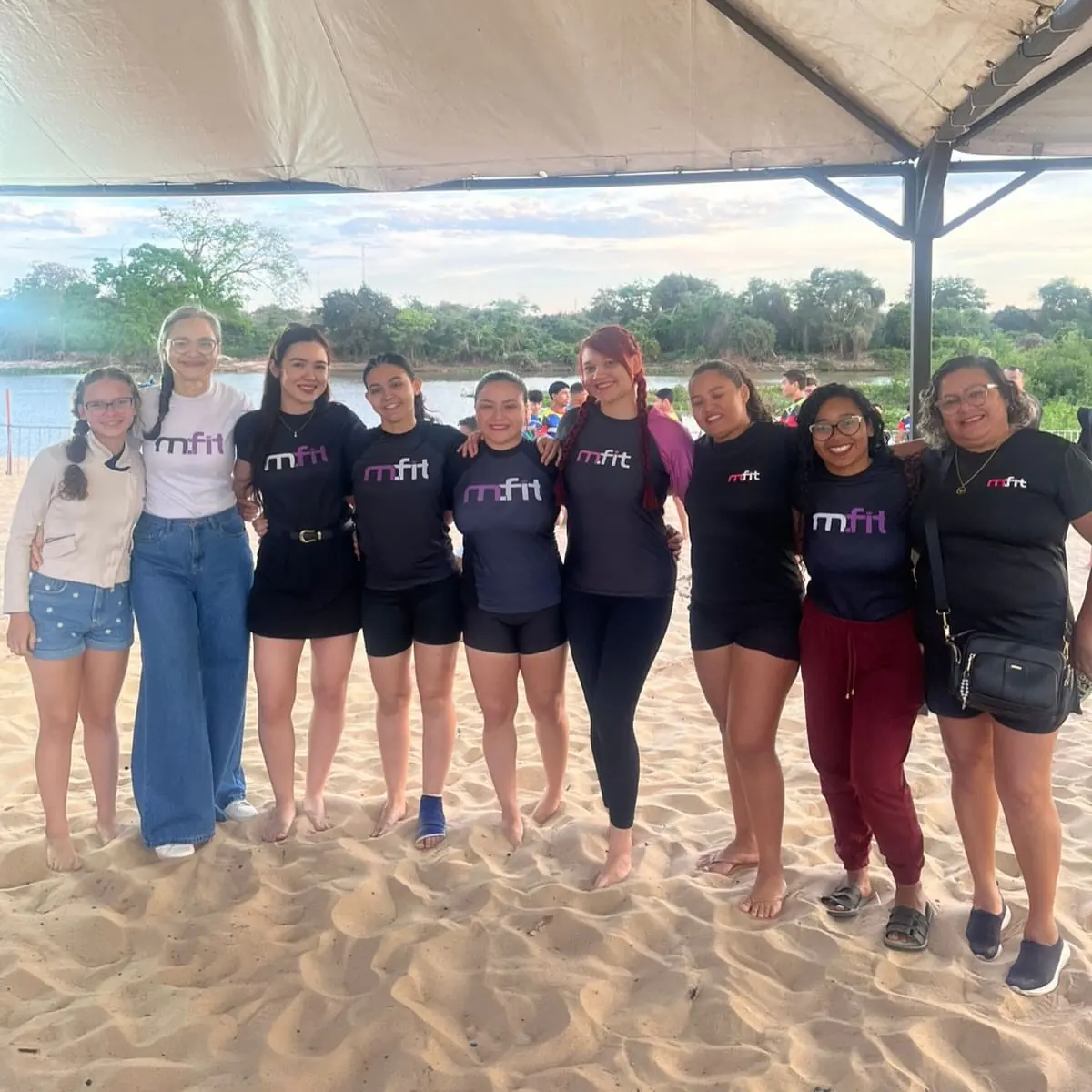 Alunas da MFIT de camiseta da academia em um evento na praia do rio