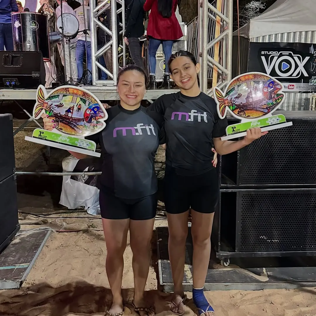 Duas alunas da MFIT no palco segurando troféus de premiação