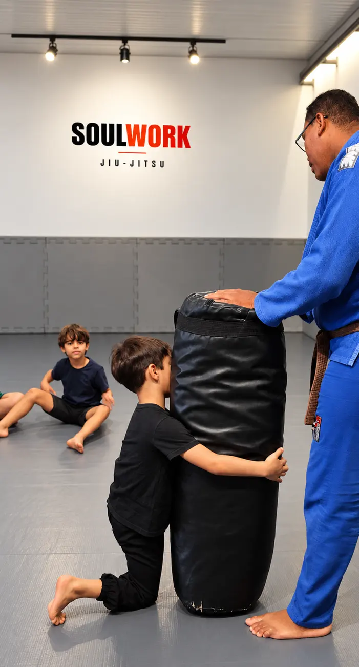 Menino treinando com o saco de pancada enquanto o professor da Soul Work segura