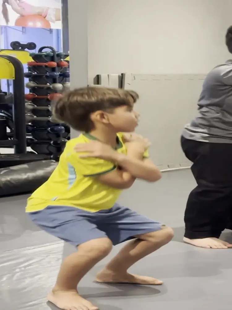 Meninos da Soul Work Kids fazendo agachamento no aquecimento do treino